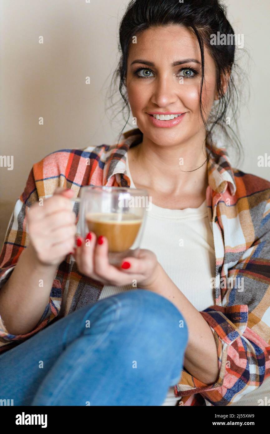 Blauäugige Frau mittleren Alters, die mit einer Tasse Kaffee sitzt Stockfoto