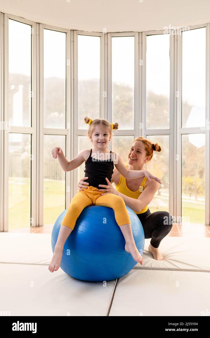 Die junge, fitnesstauglich Mutter und ihre Tochter haben Spaß mit einem Fitnessball im Fitnessstudio Stockfoto