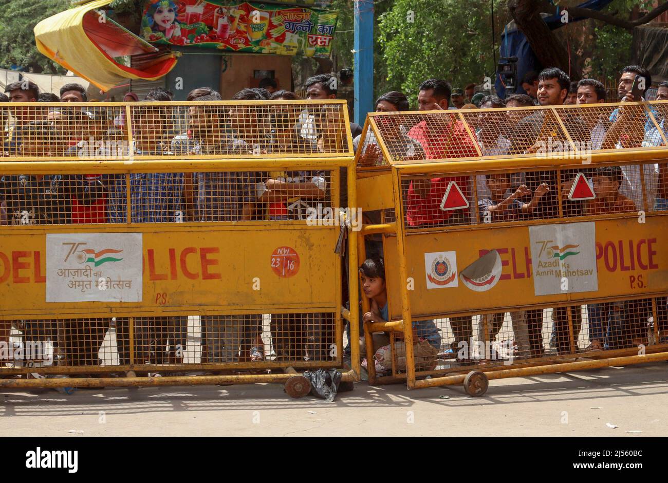 Neu-Delhi, Indien. 20. April 2022. Anwohner stehen hinter den Polizeibarrikaden, während ein Bulldozer während einer gemeinsamen Anti-Aschroadment-Kampagne der North Delhi Municipal Corporation (MCD) im Gebiet Jahangirpuri eine illegale Struktur zerstört. (Bild: © Naveen Sharma/SOPA Images via ZUMA Press Wire) Stockfoto