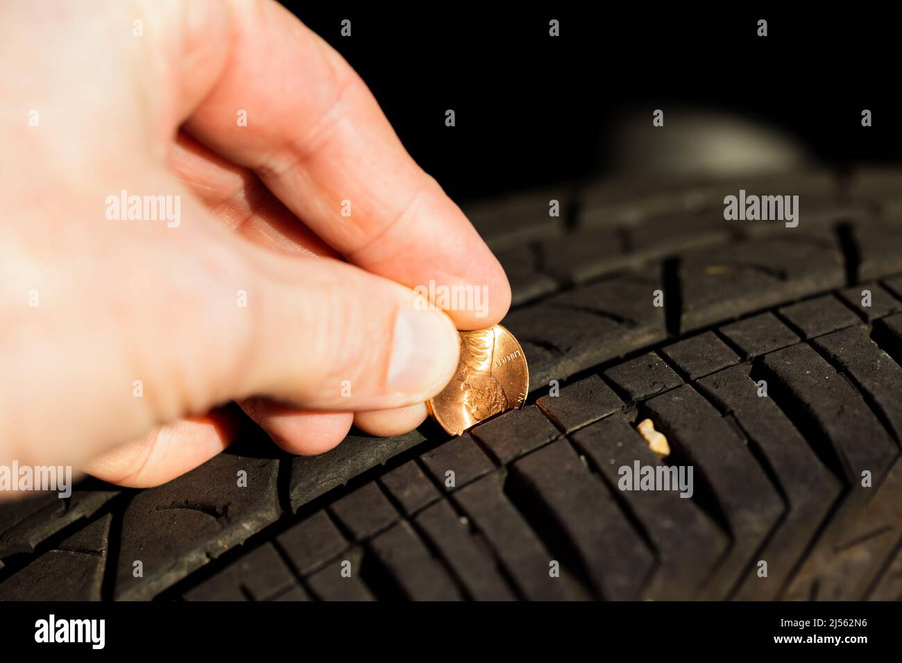 Mit einem Pfennig die Profiltiefe eines Reifens überprüfen Stockfoto
