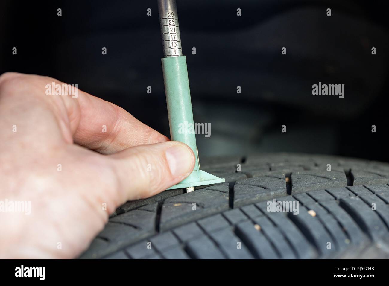 Mit einem Reifenpegelmesser die Profiltiefe eines Reifens prüfen Stockfoto