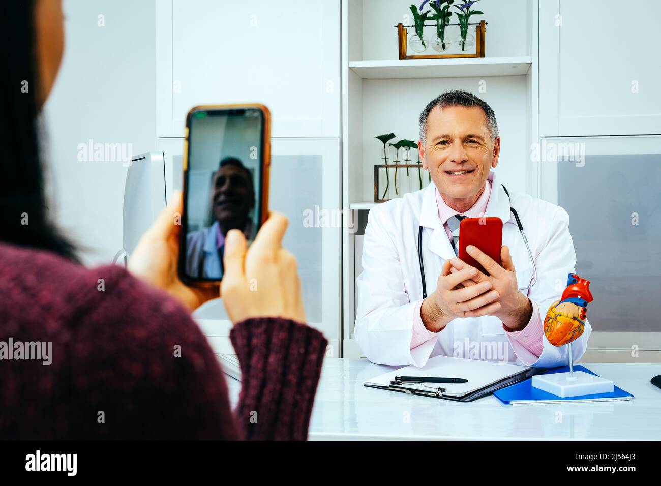 Arzt und Patient diskutieren über etwas mit Smartphones in der Krankenhausbranche Stockfoto