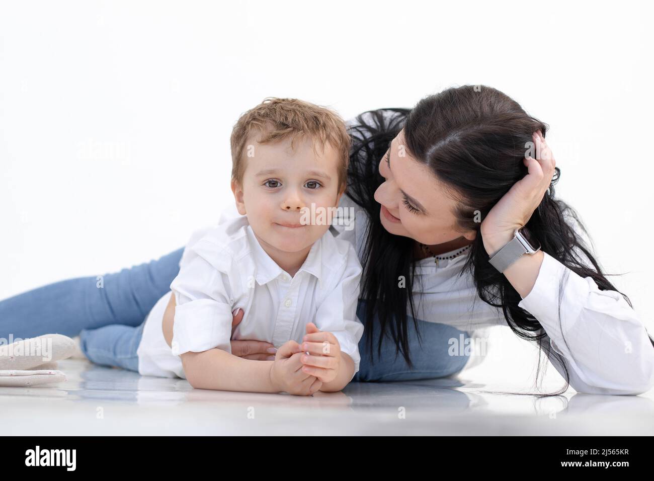 Glücklich lächelnde Frau und Junge liegen auf dem Boden, weißer Hintergrund. Umarmen, reden fürsorgliche Elternschaft. Autismus-Spektrum. Schließen Stockfoto