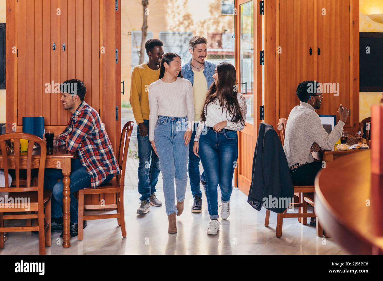 Lächelnde, multiethnische Gruppe, die eine Bar betreten hat Stockfoto
