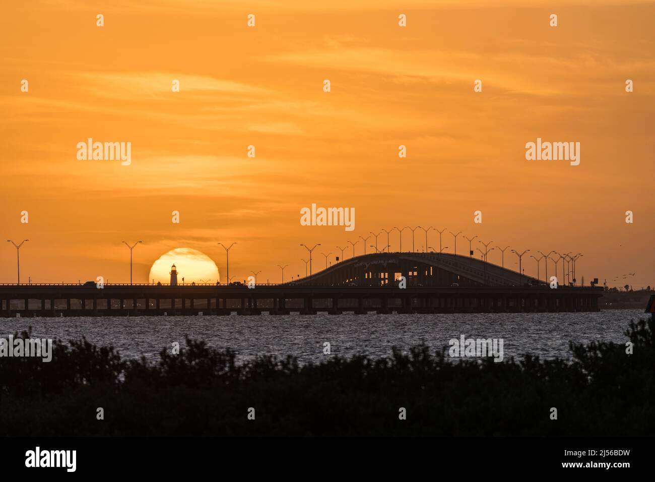 Der Port Isabel Leuchtturm vor der untergehenden Sonne mit der Queen Isabella Memorial Bridge auf der rechten Seite. Texas. Blick über die Laguna Madre f Stockfoto