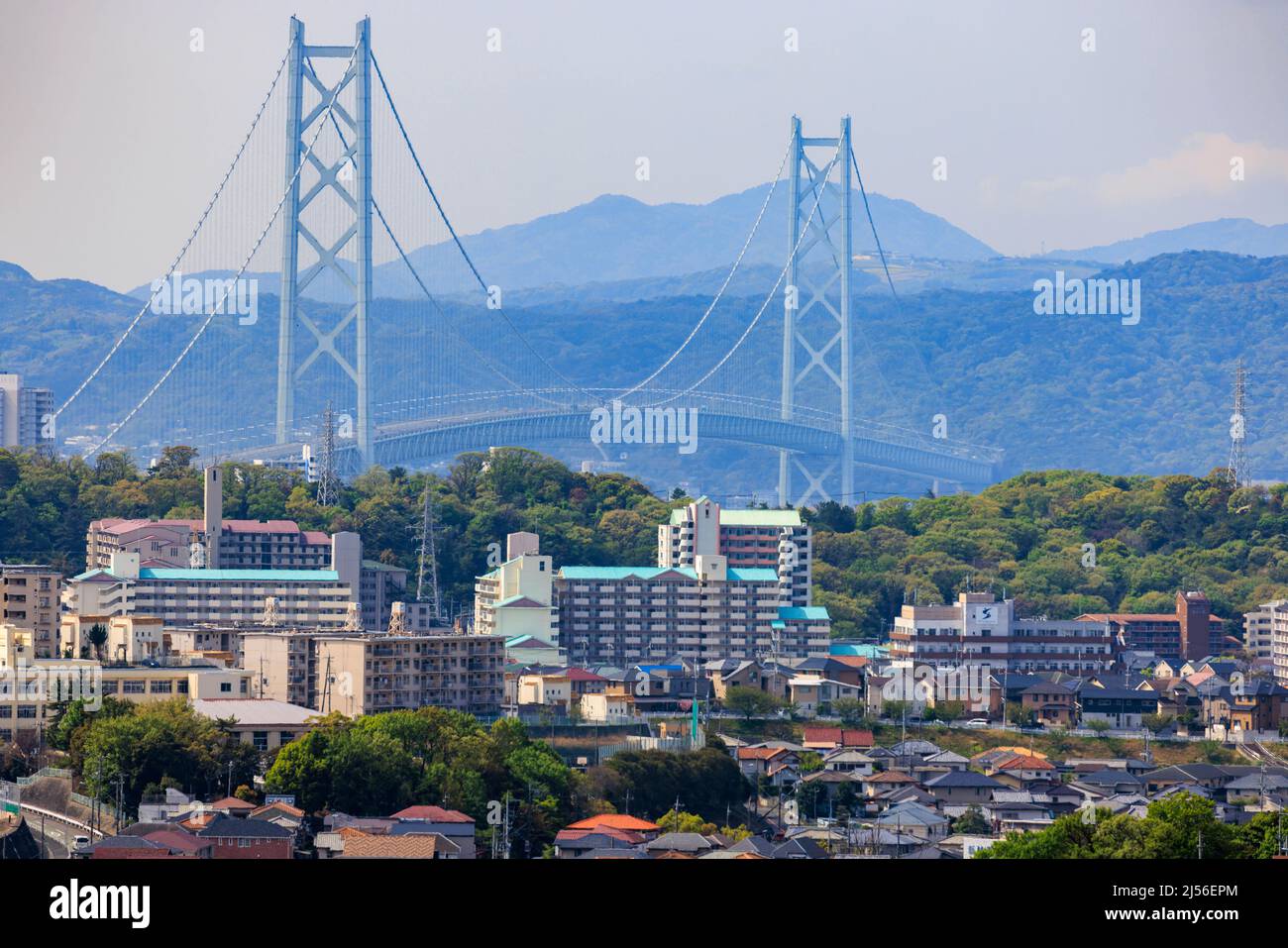 Die Hängebrücke ragt hoch über weitläufige Vororte und Wohnblocks Stockfoto