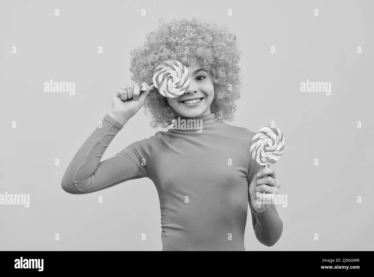 Happy girl Kind mit orangen Haaren in rosa Poloneck haben Spaß halten Lutscher, Mädchenschaft Stockfoto