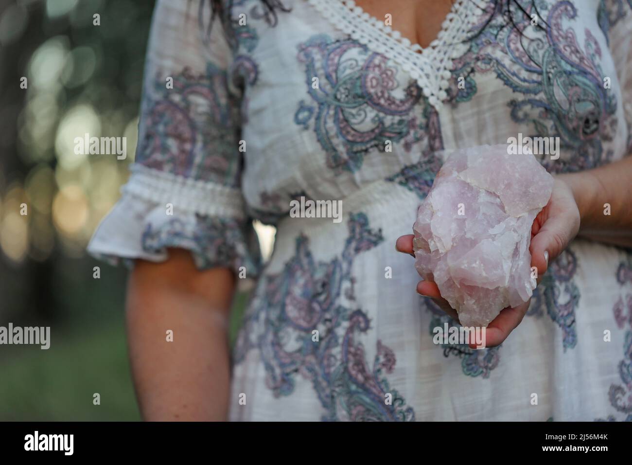 Nahaufnahme des rosa Quarzgesteins in der Hand der Frau Stockfoto