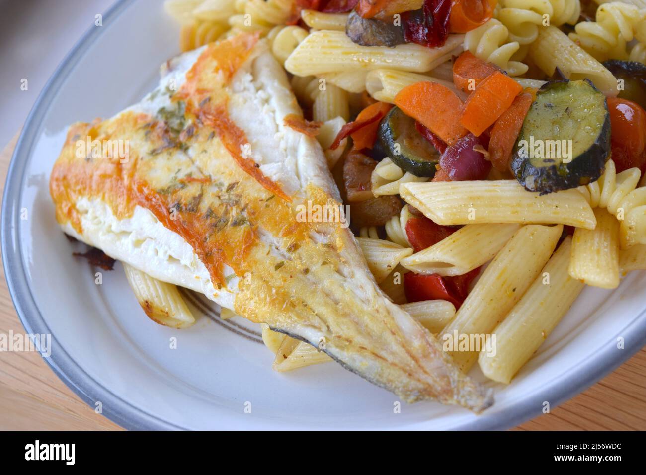 Helles Gericht mit gekochtem weißen Fisch, Nudeln, Auberginen und Karotten. Stockfoto