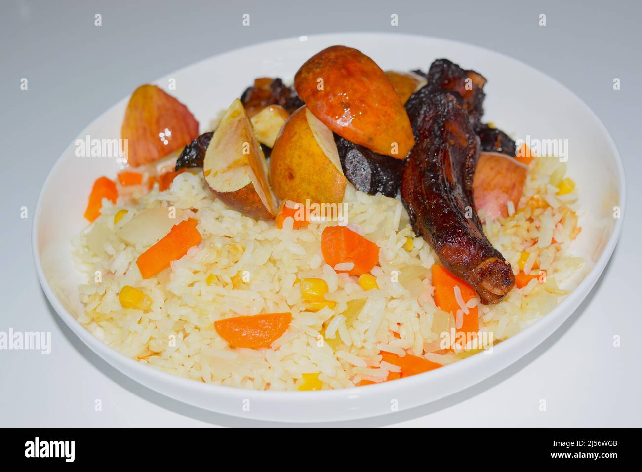 Serviert Gericht mit Schweinefleischrippen, Äpfeln, Reis und Gemüse. Stockfoto