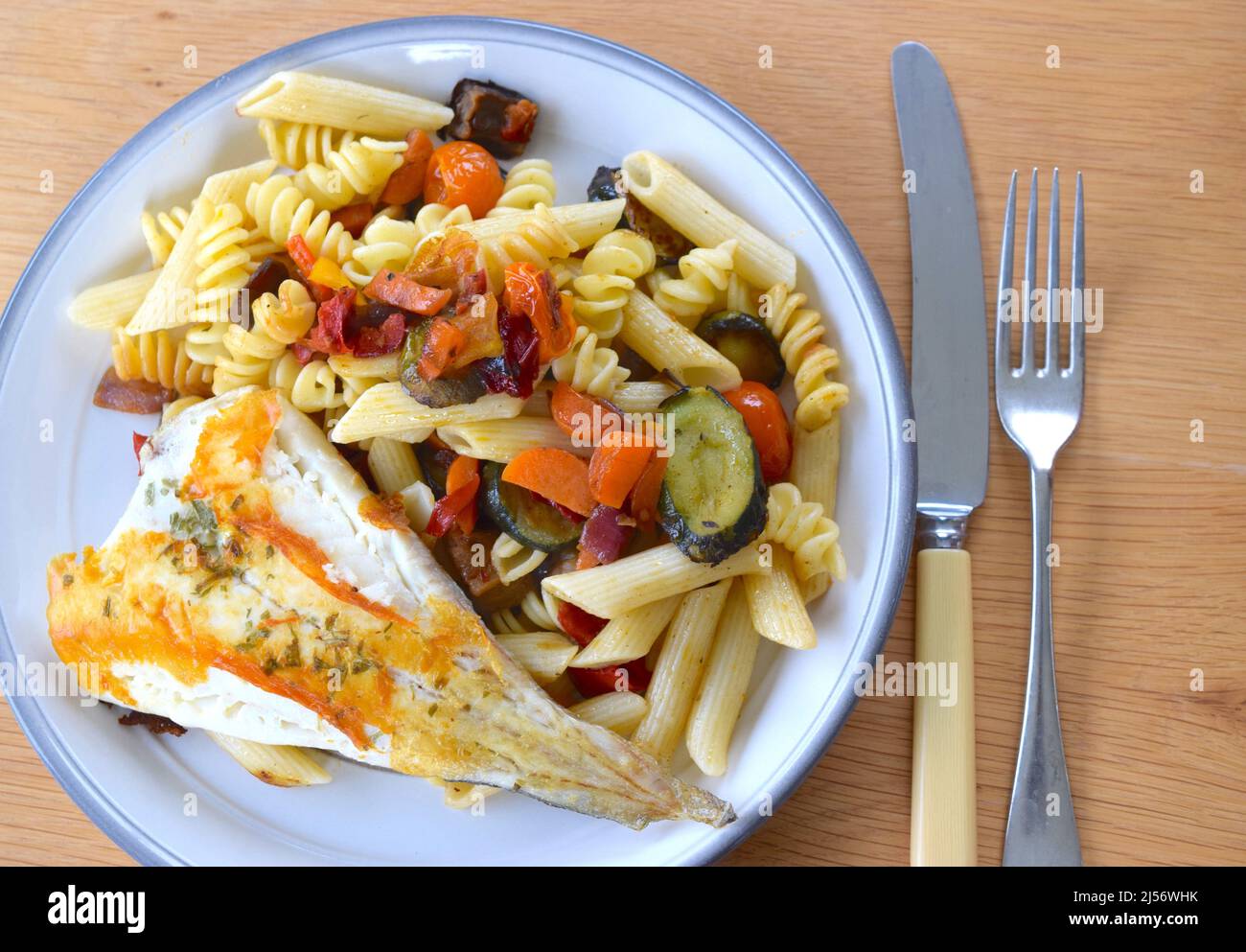 Helles Gericht mit gekochtem weißen Fisch, Nudeln, Auberginen und Karotten. Stockfoto