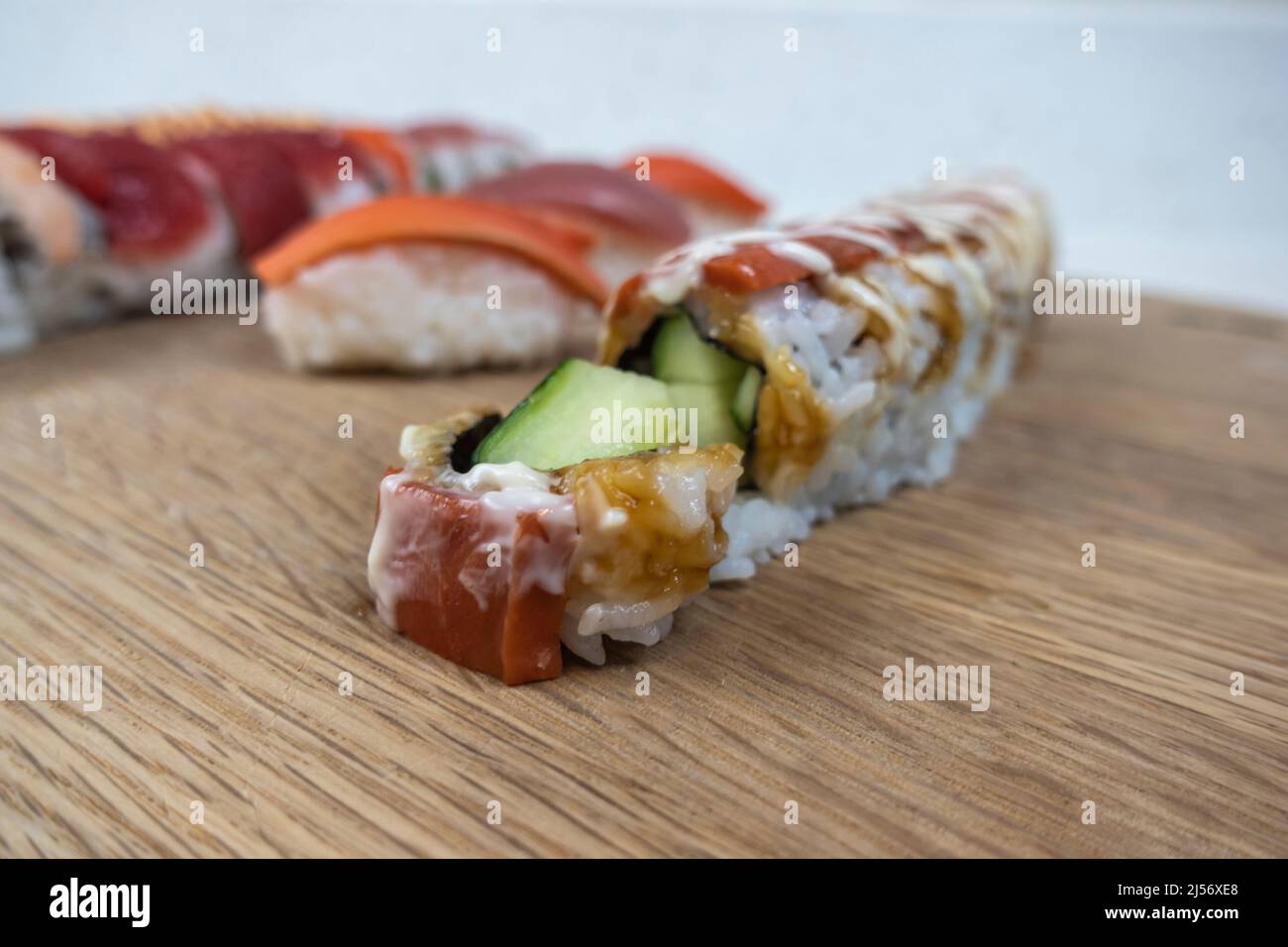 Abgewinkelte, selektive Fokusansicht einer Vielzahl von Sushi-Rollen auf einem Bambus-Schneidebrett Stockfoto