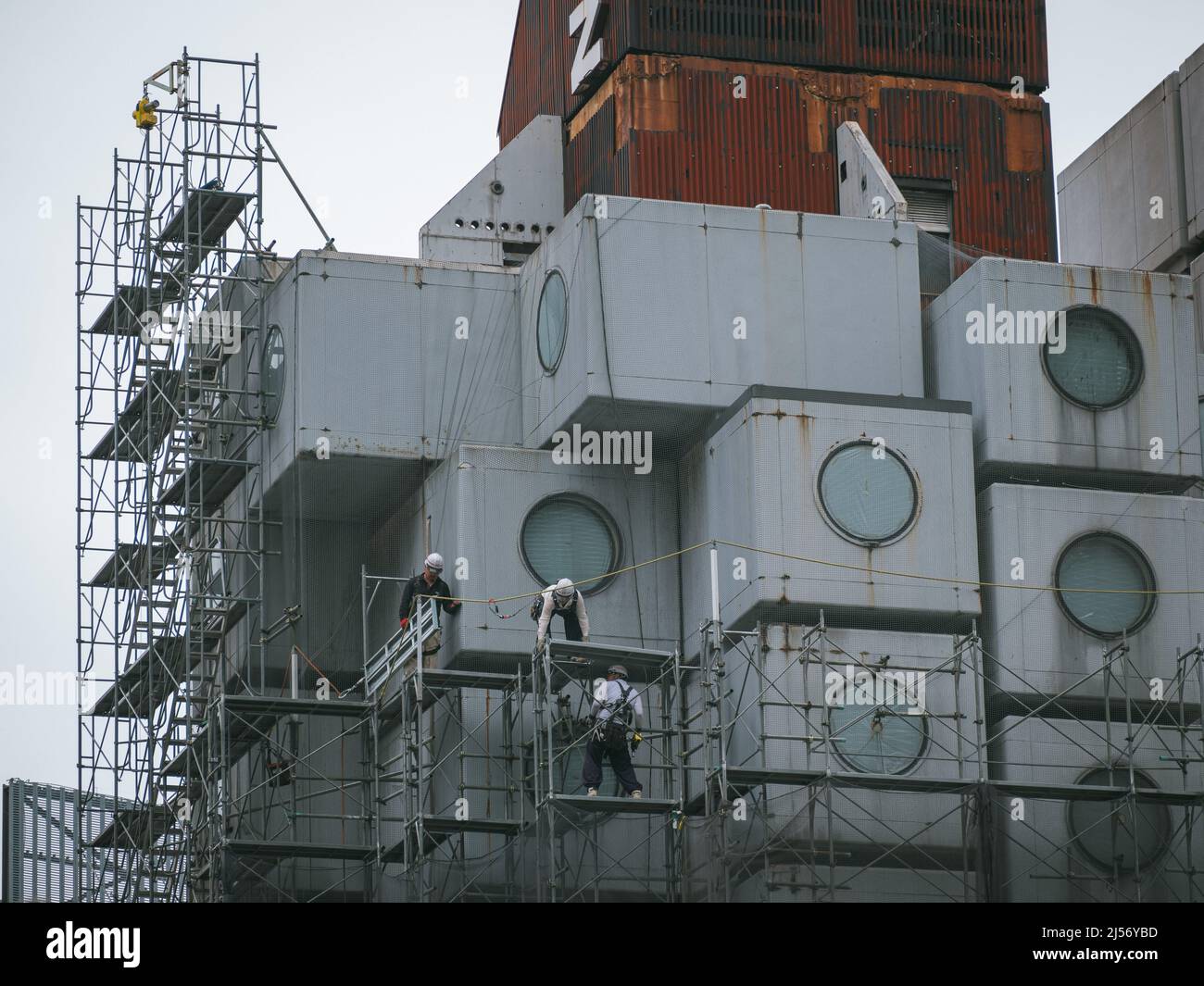Bauarbeiter bauen Gerüste ein, während die Arbeiten beginnen, den Wahrzeichen Nakagin Capsule Tower abzureißen, ein Wohn- und Bürogebäude, das Anfang 1970s gebaut wurde und ein Beispiel für Japans Architekturdesign-Bewegung der Nachkriegszeit, bekannt als Metabolism, am 20. April 2022 im Tokioter Stadtteil Ginza ist.20. April 2022 Quelle: Nicolas Datiche/AFLO/Alamy Live News Stockfoto