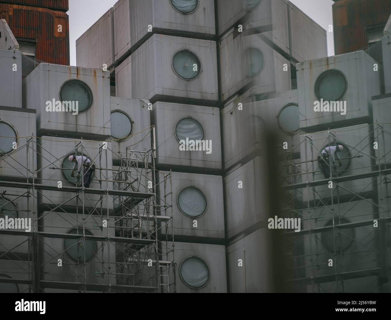 Bauarbeiter bauen Gerüste ein, während die Arbeiten beginnen, den Wahrzeichen Nakagin Capsule Tower abzureißen, ein Wohn- und Bürogebäude, das Anfang 1970s gebaut wurde und ein Beispiel für Japans Architekturdesign-Bewegung der Nachkriegszeit, bekannt als Metabolism, am 20. April 2022 im Tokioter Stadtteil Ginza ist.20. April 2022 Quelle: Nicolas Datiche/AFLO/Alamy Live News Stockfoto