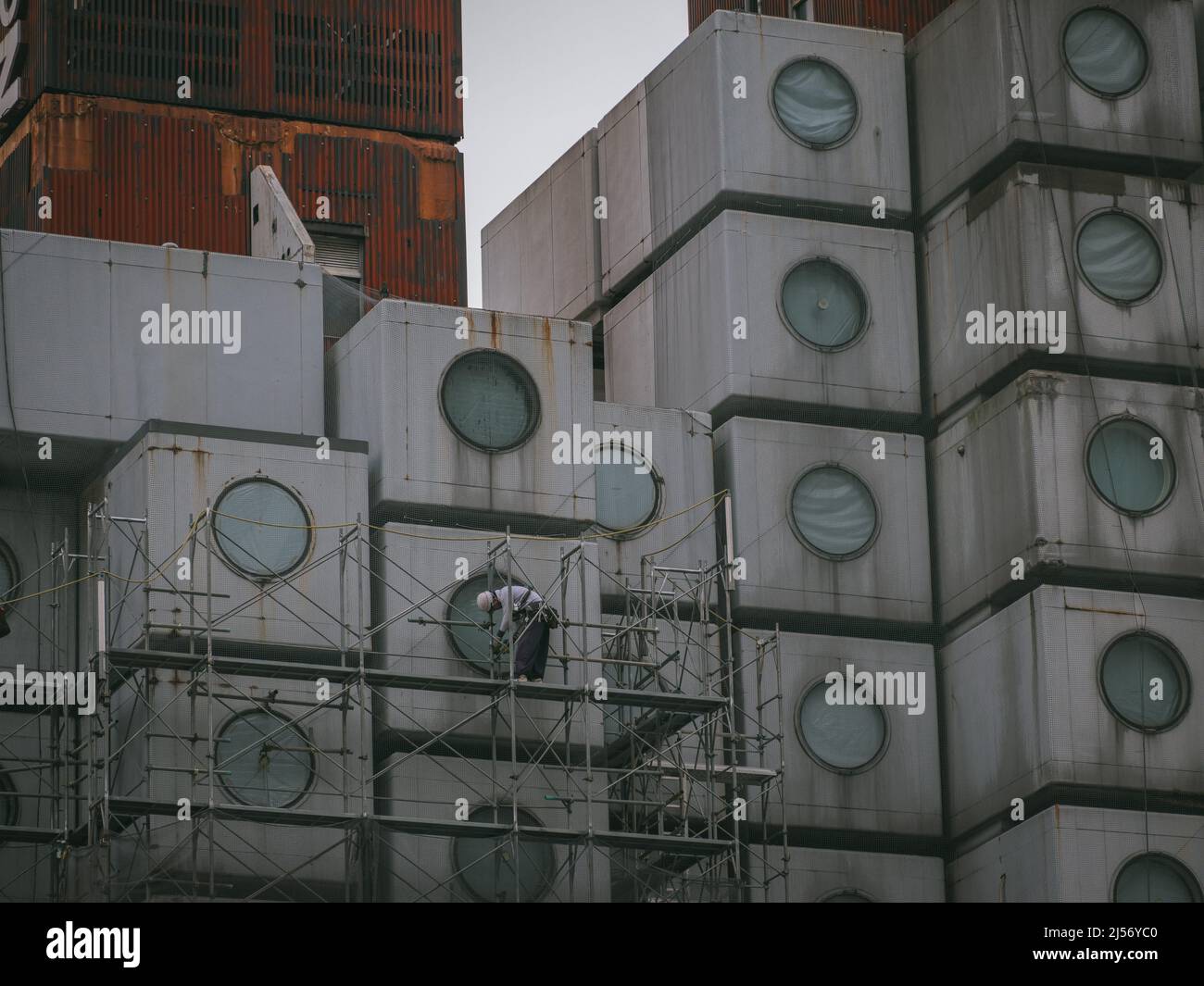 Bauarbeiter bauen Gerüste ein, während die Arbeiten beginnen, den Wahrzeichen Nakagin Capsule Tower abzureißen, ein Wohn- und Bürogebäude, das Anfang 1970s gebaut wurde und ein Beispiel für Japans Architekturdesign-Bewegung der Nachkriegszeit, bekannt als Metabolism, am 20. April 2022 im Tokioter Stadtteil Ginza ist.20. April 2022 Quelle: Nicolas Datiche/AFLO/Alamy Live News Stockfoto