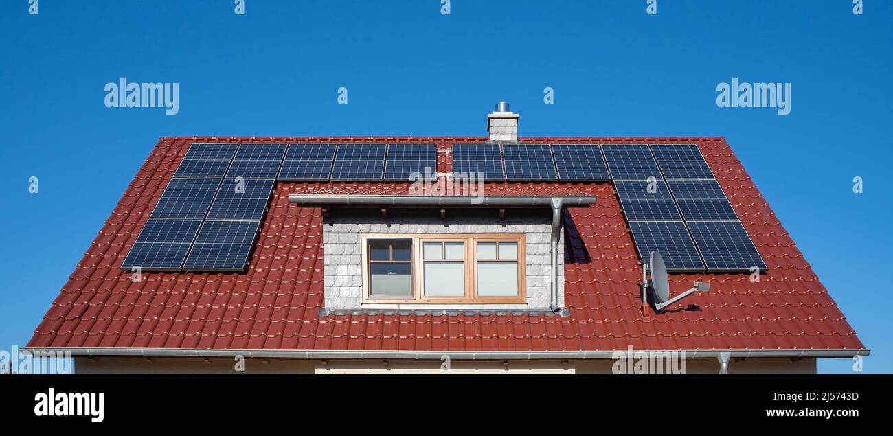 Rotes Ziegeldach eines Hauses mit Sonnenkollektoren einer Photovoltaikanlage Stockfoto