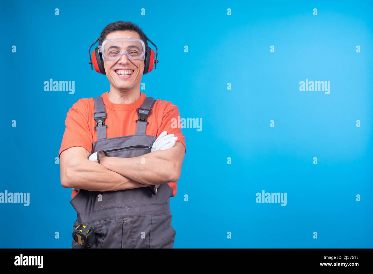 Fröhlicher Zimmermann mit schützenden Accessoires lachend über Witz Stockfoto