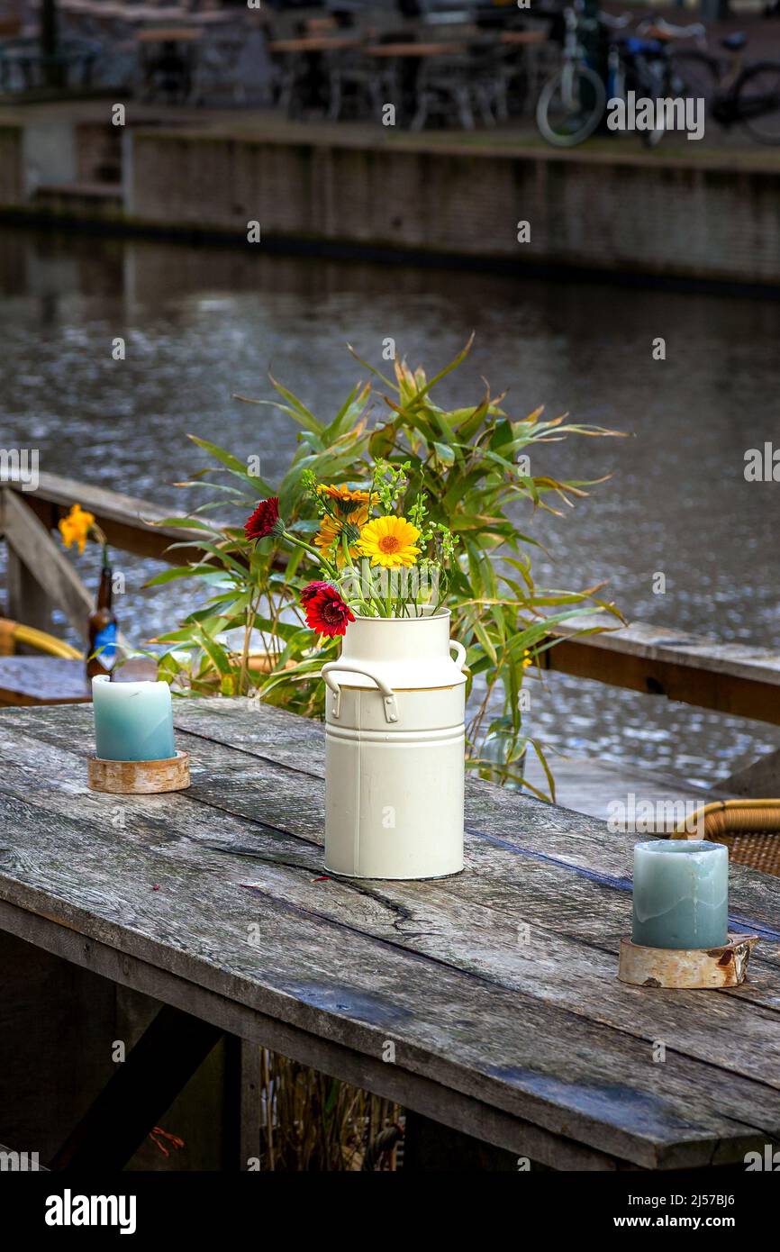 Gemütliches Straßencafé Holztisch mit Blumen in Vase. Einrichtung im Freien mit Kerzen in den Niederlanden Stockfoto