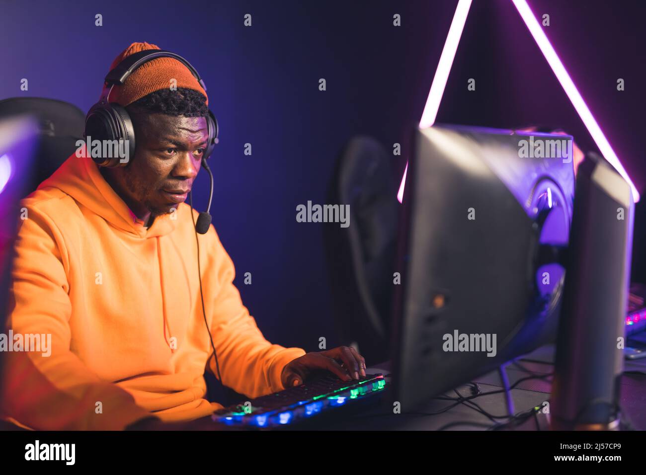 Attraktive afroamerikanische Spieler in orange Hoodie und Kappe spielen Videospiele kopieren Raum . Hochwertige Fotos Stockfoto