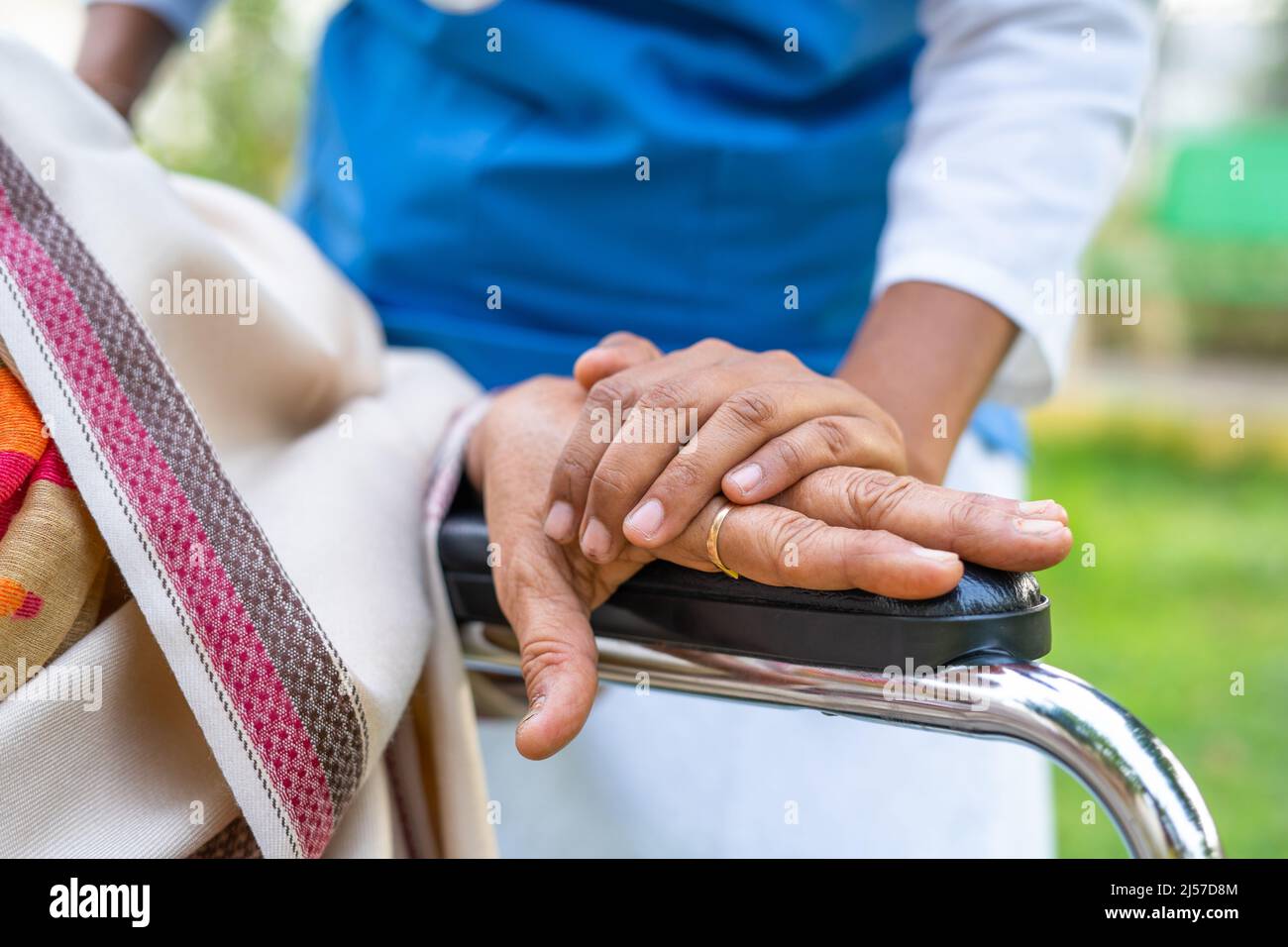 Nahaufnahme der Hände des Arztes, die die eldery trösten, indem sie die Hand am Rollstuhl halten - Konzept von Mitgefühl, Empathie und Fürsorger. Stockfoto