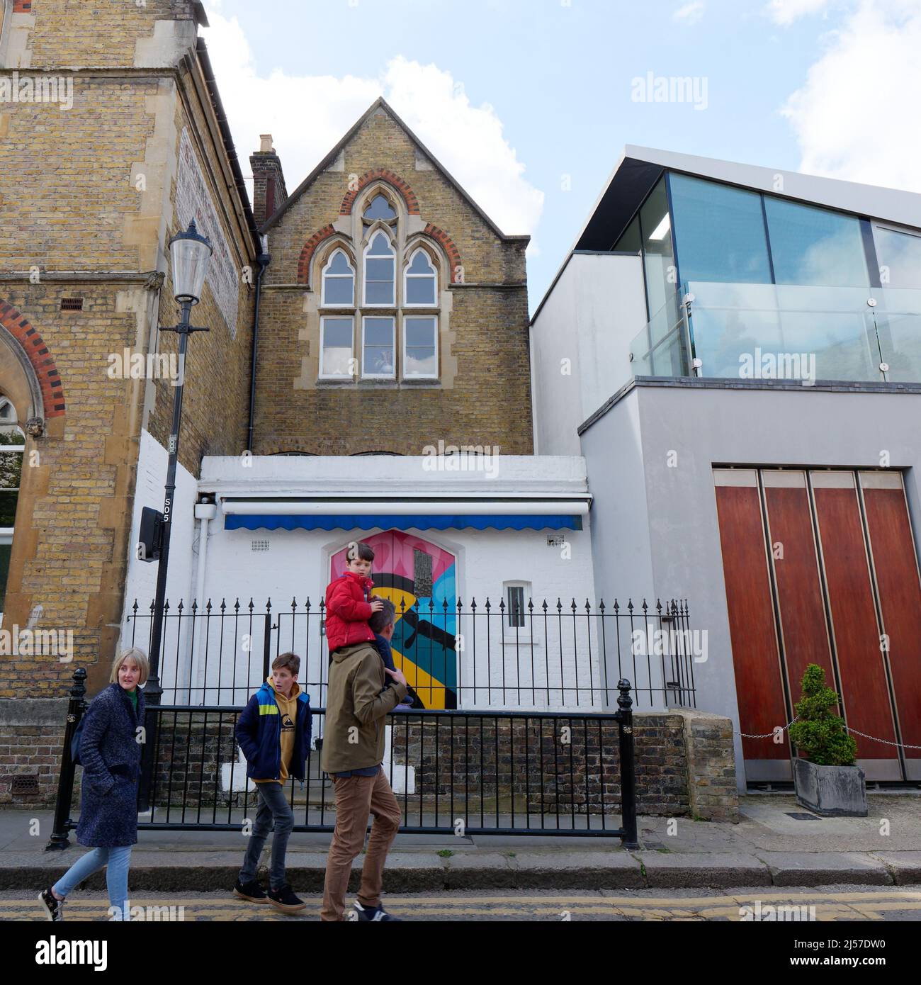 London, Greater London, England, April 09 2022: Junge mit einem Sparschwein in der Portabello Road in Notting Hill mit der St. Peters Church dahinter. Stockfoto