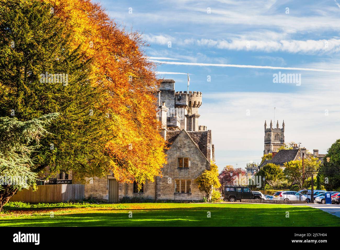 Wunderschöne Herbstfarben im Cirencester Park auf dem Bathhurst Estate in Gloucestershire. Der Turm der Kirche von Johannes dem Täufer und ein Teil der Stockfoto
