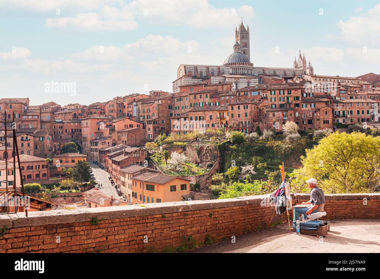 Panoramablick auf die Stadt Siena und die Kathedrale an einem sonnigen Tag. Ein Maler malt einen Blick auf Siena in der Luft. Stockfoto