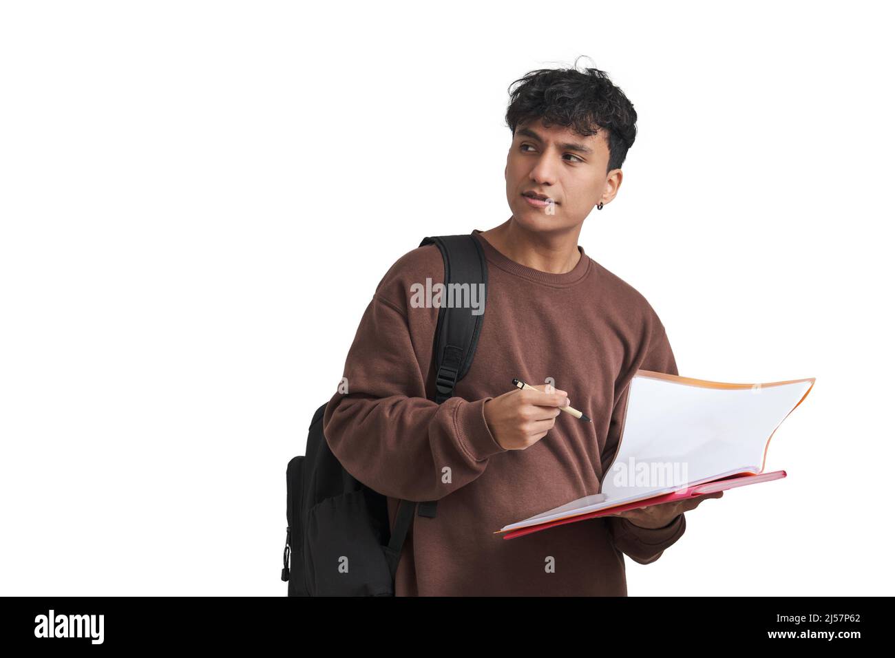 Junge peruanische Studentin, die isoliert auf eine Seite schaut, die Stift und Ordner hält. Stockfoto