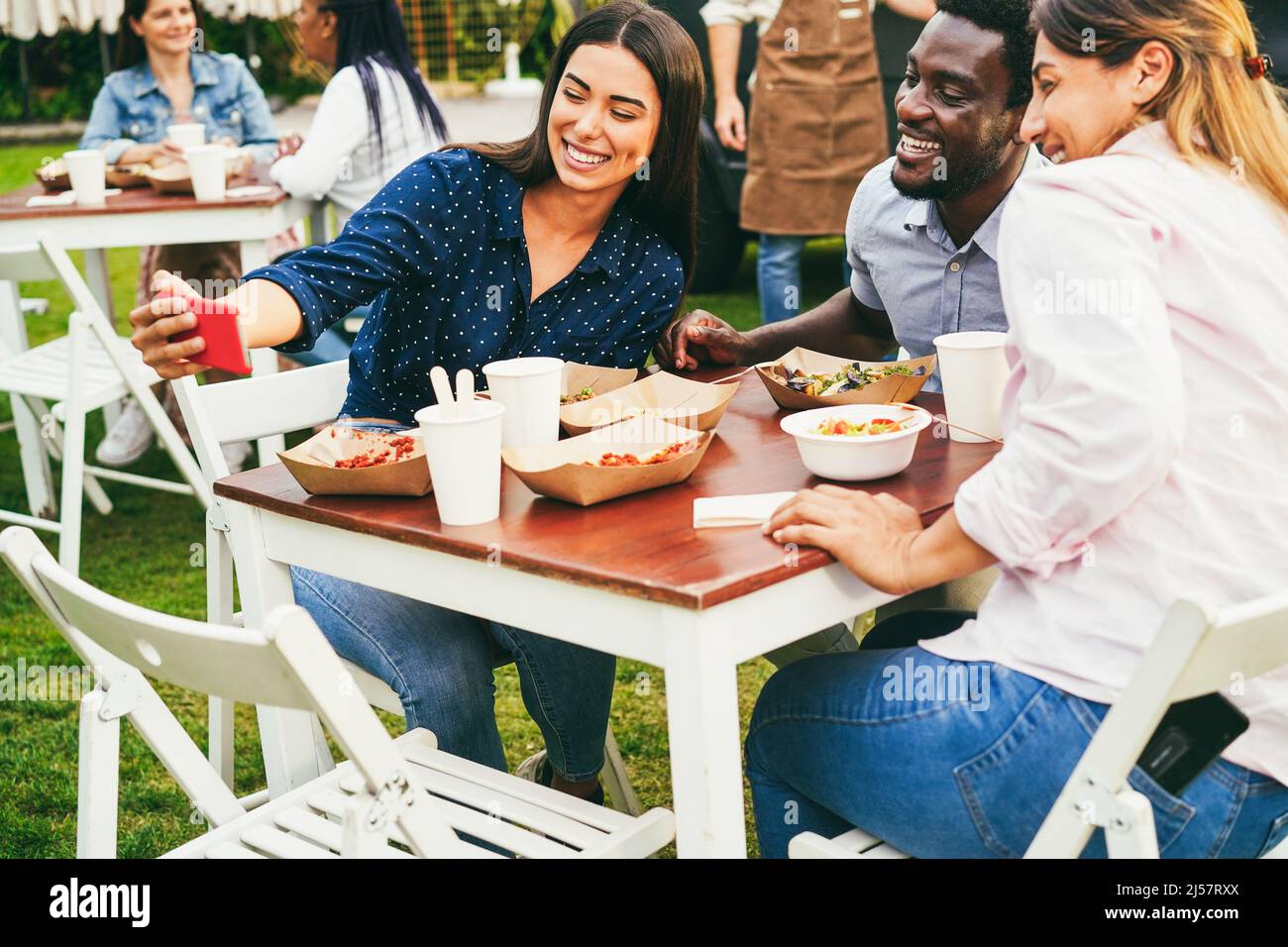 Multirassische Menschen, die Spaß haben, Selfie mit dem Mobiltelefon im Food Truck Restaurant im Freien zu machen - Fokus auf Mädchen Gesicht Stockfoto