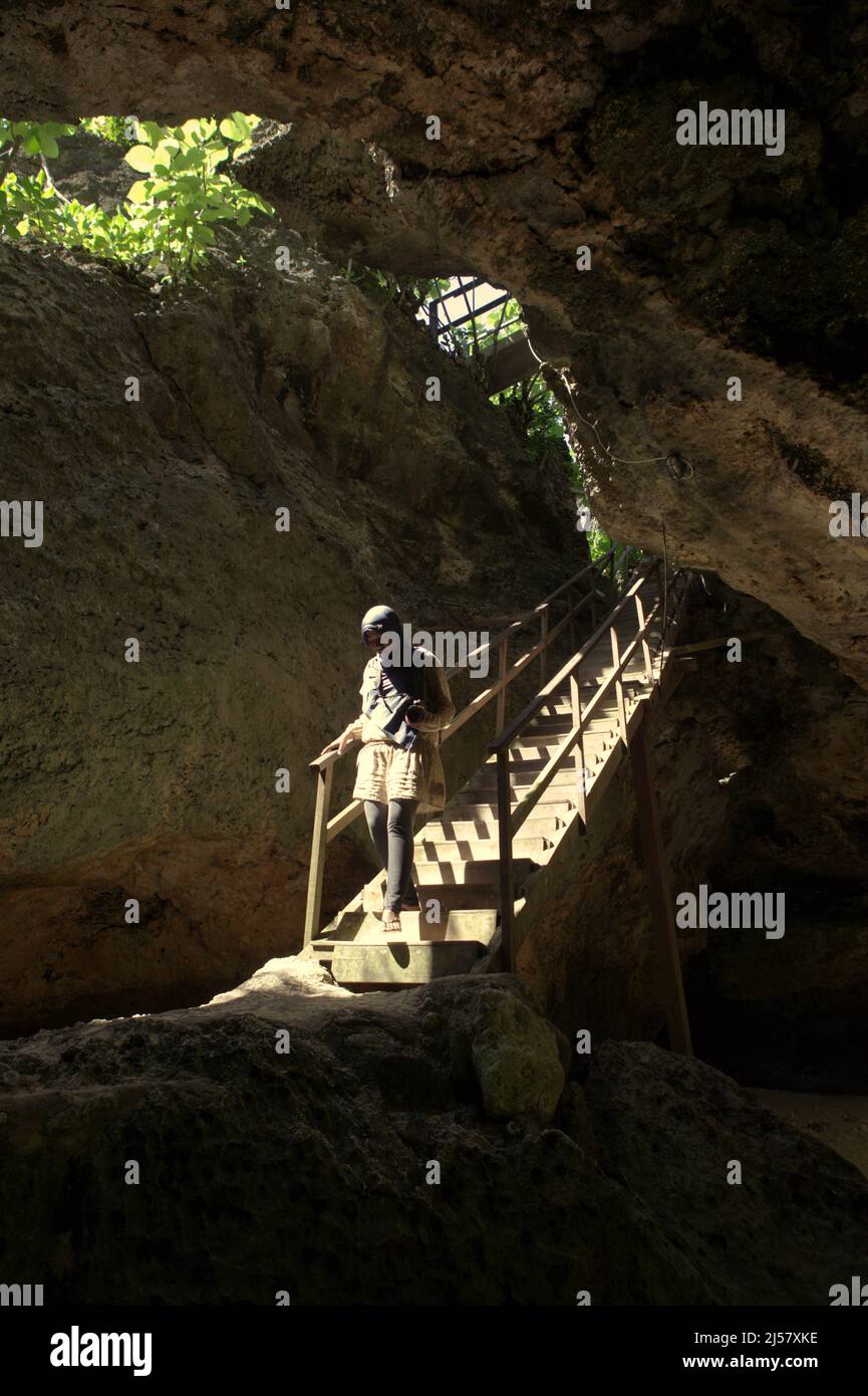 Eine Frau, die eine Treppe durch eine Kalksteinhöhle hinuntergeht, die zum Strand Padang-padang in Labuan Sait, Süd-Kuta, Bali, Indonesien führt. Stockfoto