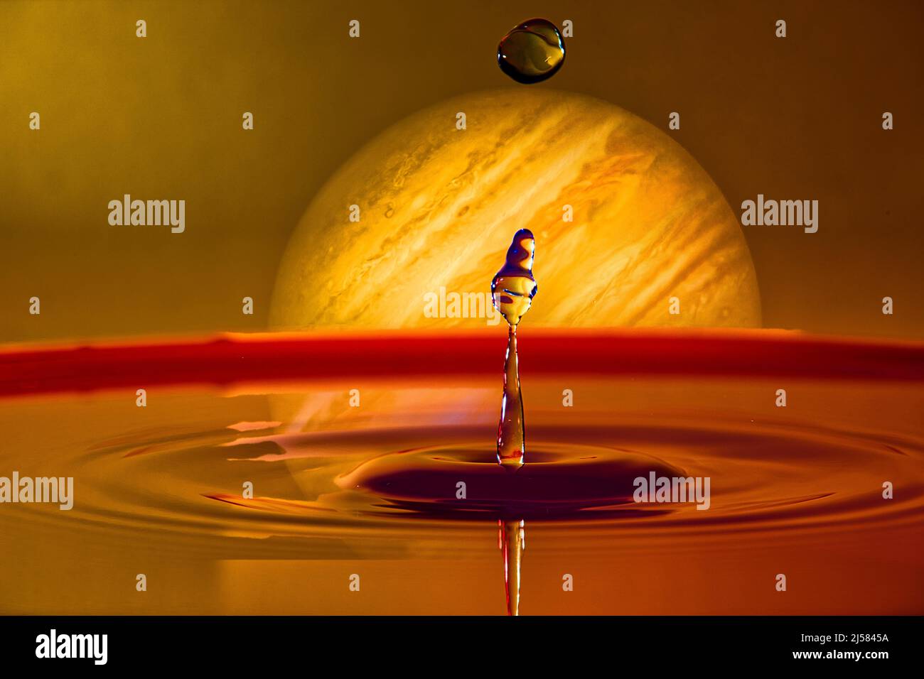 Konzept, Wasser auf einem anderen Planeten, Tropfenfotografie, Wassersäule mit Tropfen, Planet Jupiter steigt, Highspeed-Fotografie, Fantasie, Fotomontage Stockfoto