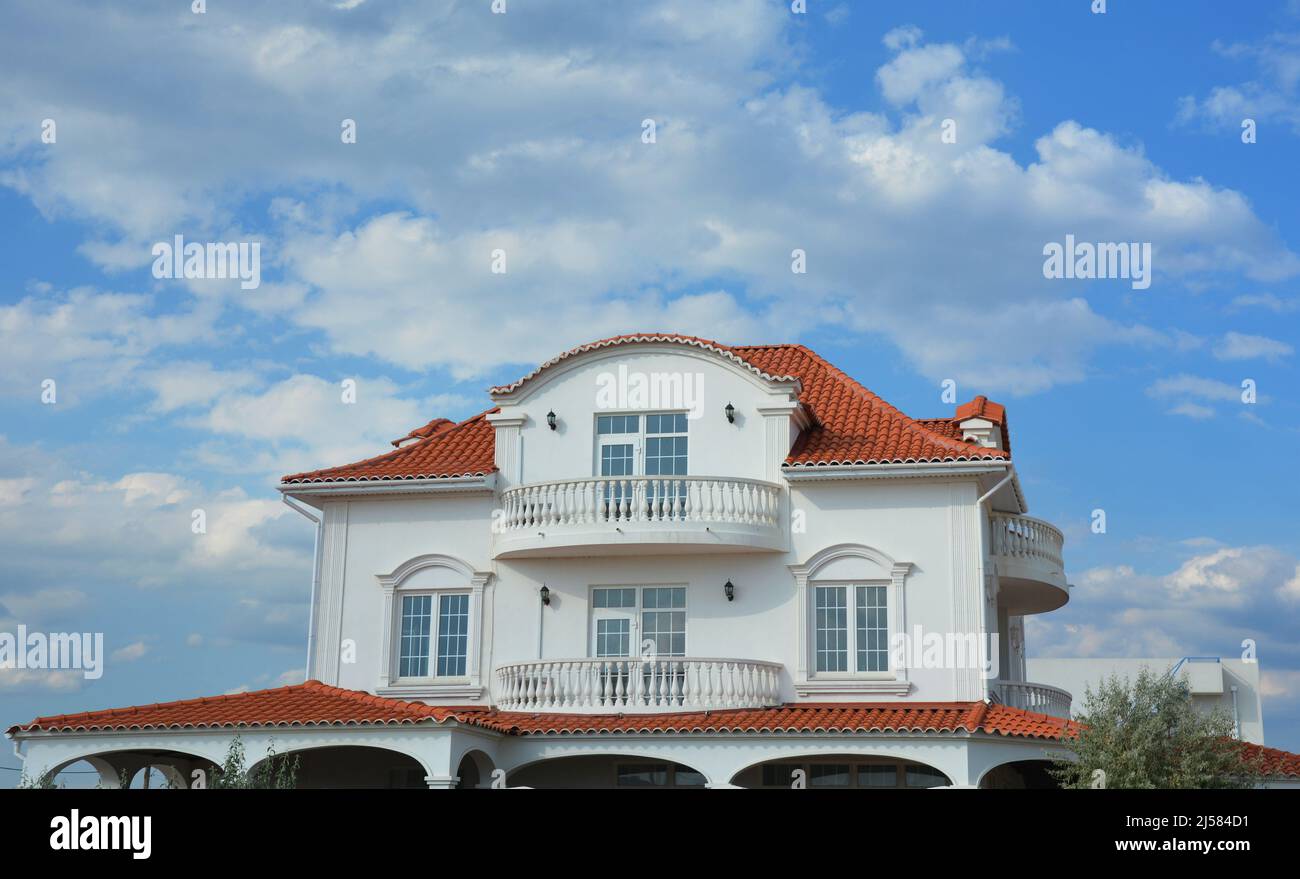 Luxuriöses modernes Haus mit Dachbalkon und rotem Ziegeldach. Luxus-Haus mit Wolken Himmel. Stockfoto