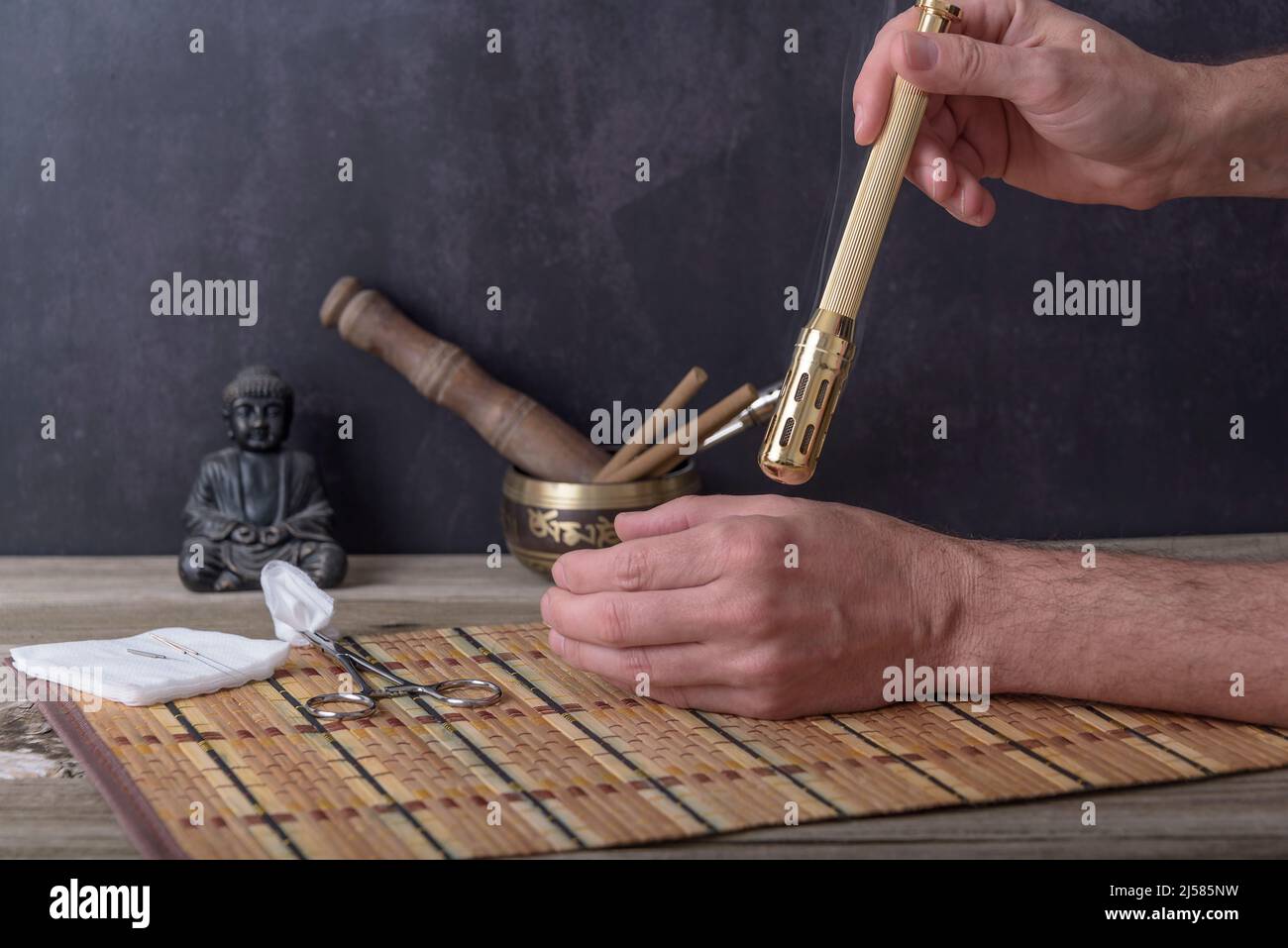 Moxibustherapie - traditionelle Chinesische Medizin. Platzierung des brennenden Moxa-Sticks auf dem Arm. Stockfoto