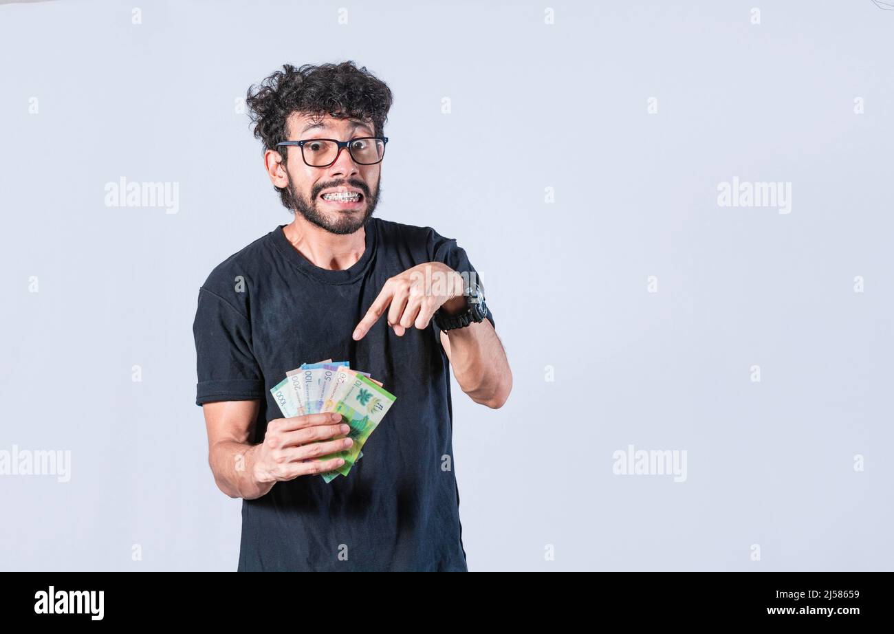 Ein Mann zeigt auf das Geld in seiner Hand, ein Mann zeigt auf Geldrechnungen in seiner Hand, Konzept von Einkommen und Ersparnissen Stockfoto