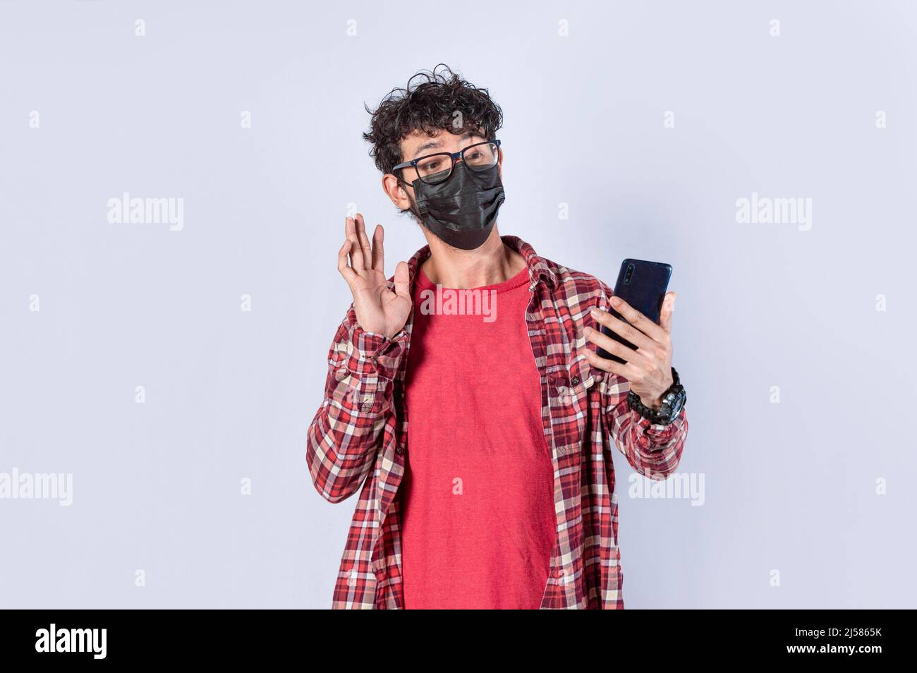 Mann macht Videoanruf isoliert, Kerl macht Videoanruf mit Gesichtsmaske, Gesichtsmaske Videoanruf Konzept Stockfoto