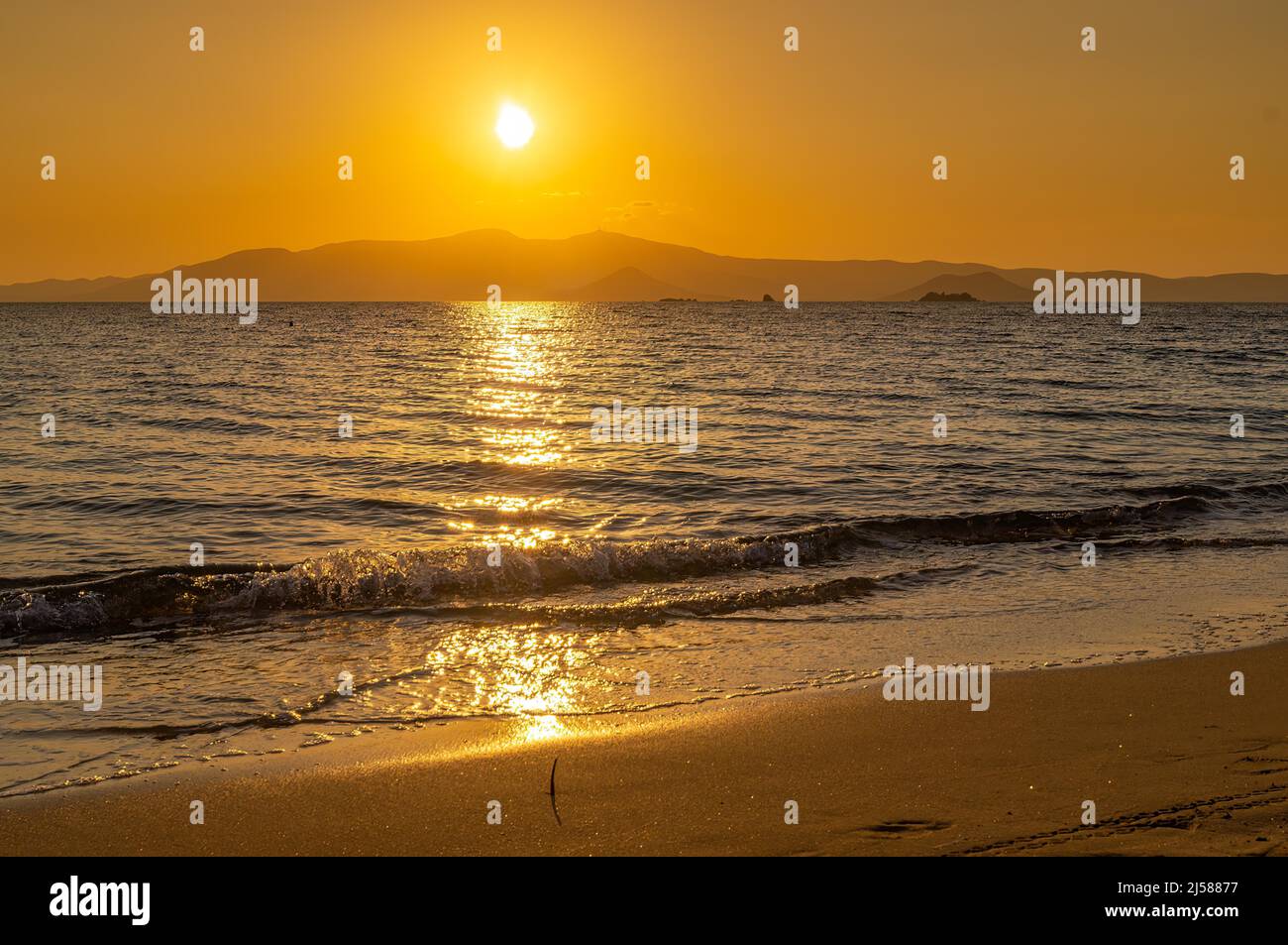 Gelber, warmer Sonnenuntergang mit einer Gebirgsformation im Hintergrund Stockfoto