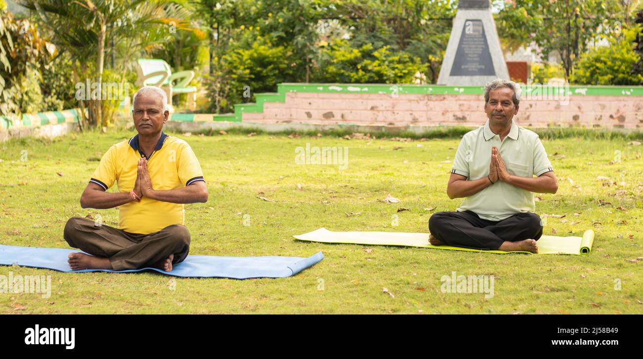 Breites Shoto von Senior man in namaste Pose auf Yoga-Matte - Konzept der älteren 60s Menschen Fitness, gesunde Lebensweise und morgendliche Routine. Stockfoto