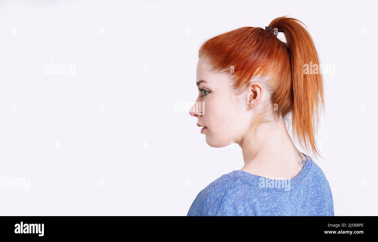 Junge Frau mit gefärbten roten Haaren, die in einem Pferdeschwanz mit Scrunchie zurückgebunden ist Stockfoto