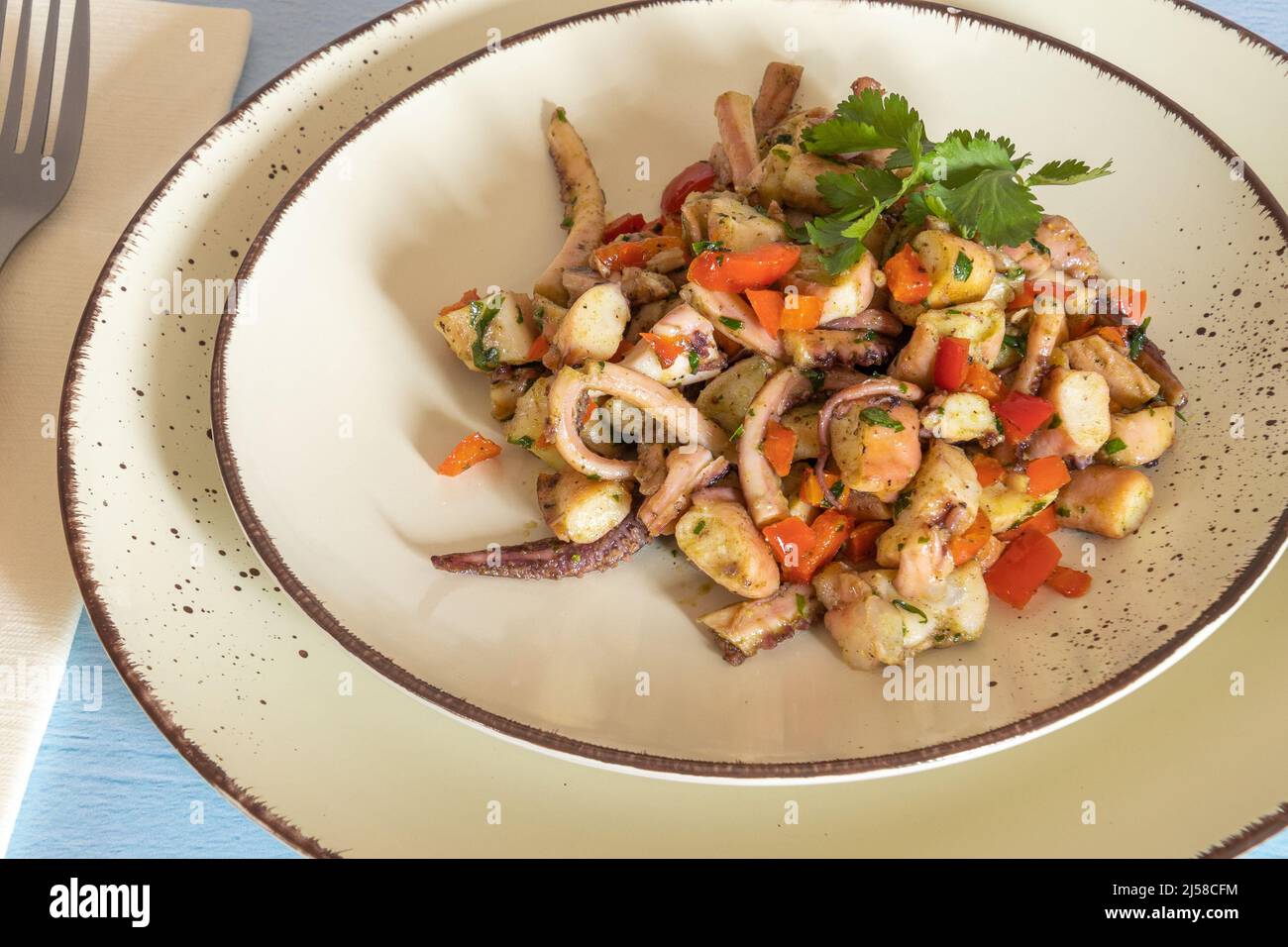 Knoblauch-Tintenfisch-Salat auf einem Teller auf einem Tisch Stockfoto