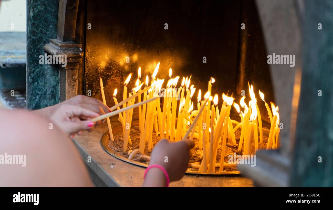 Vor einer orthodoxen Kirche auf der griechischen Insel Korfu zünden Menschen Kerzen an Stockfoto