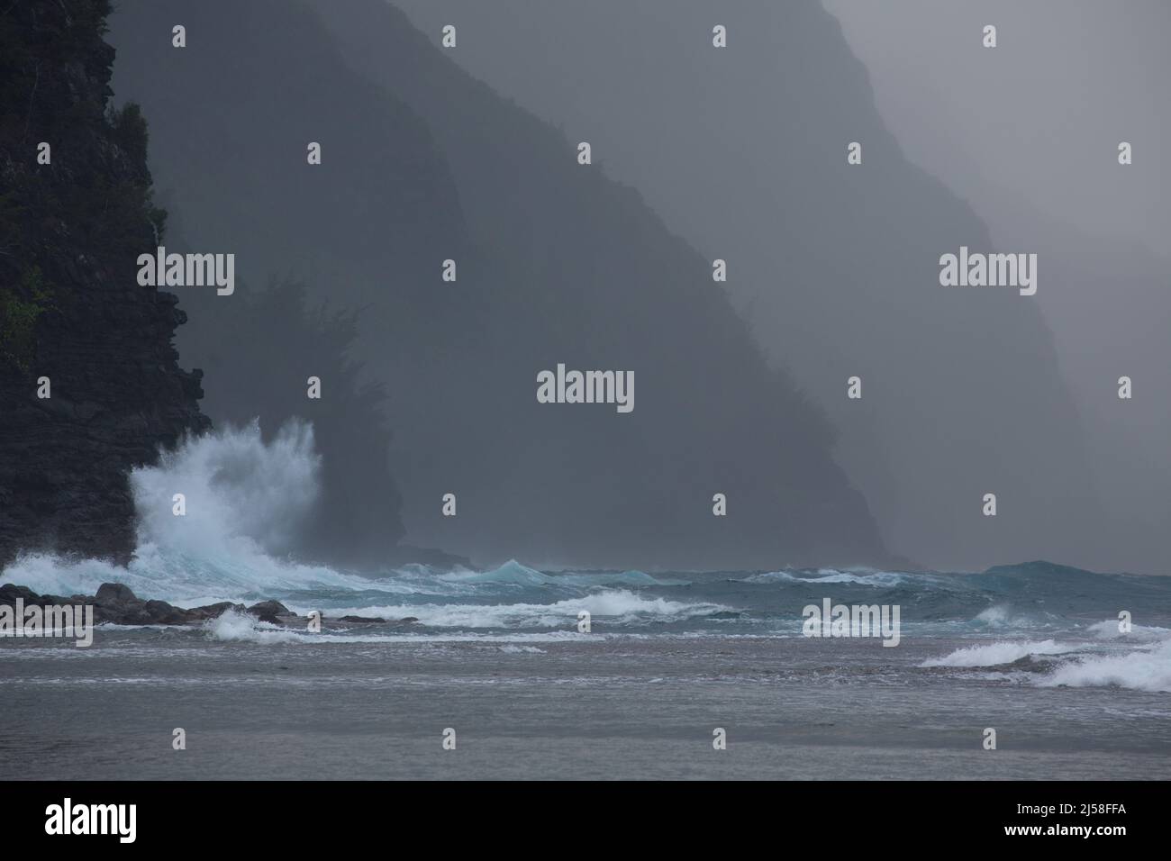 Eine Welle stürzt heftig auf die felsigen Klippen der Na Pali Küste im Na Pali Coast State Park auf Kauai, Hawaii. Stockfoto