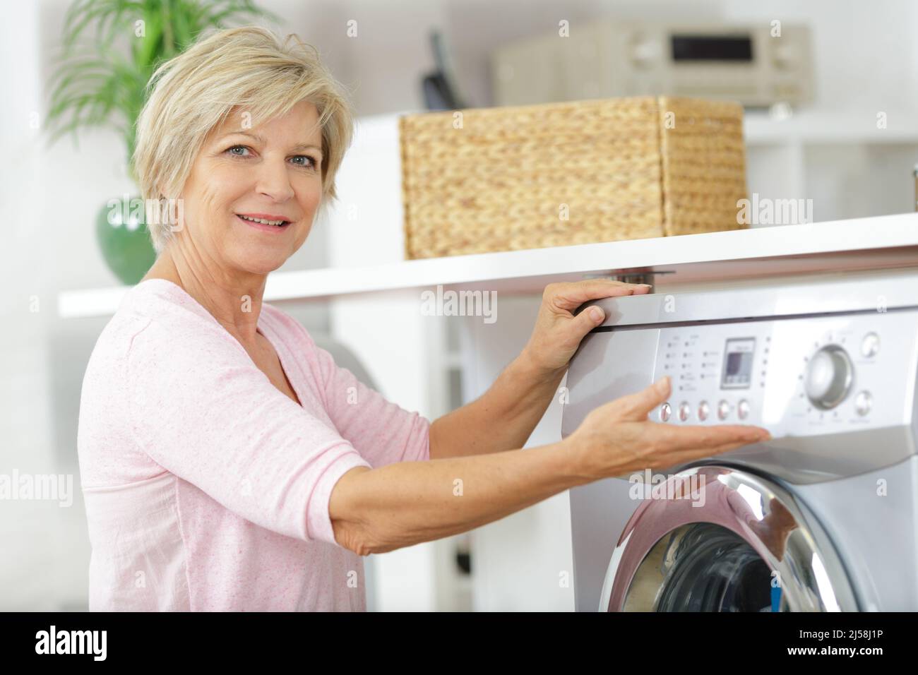 Reife Frau zeigt ihre Waschmaschinensteuerung Stockfoto