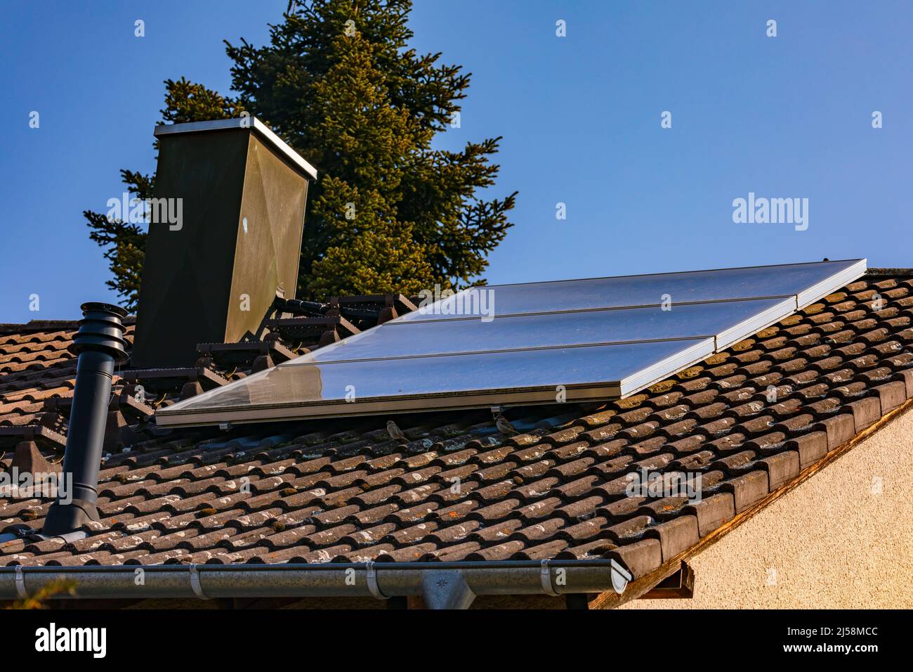 Sonnenkollektoren auf dem Dach eines Hauses verwandeln Strahlung in heißes Wasser Stockfoto