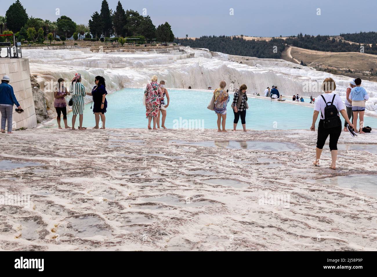 PAMUKKALE, TÜRKEI - 1. JUNI 2021: Nicht identifizierte Touristen laufen barfuß durch Travertin-Becken, die aus Kalksteintuff geformt sind. Stockfoto
