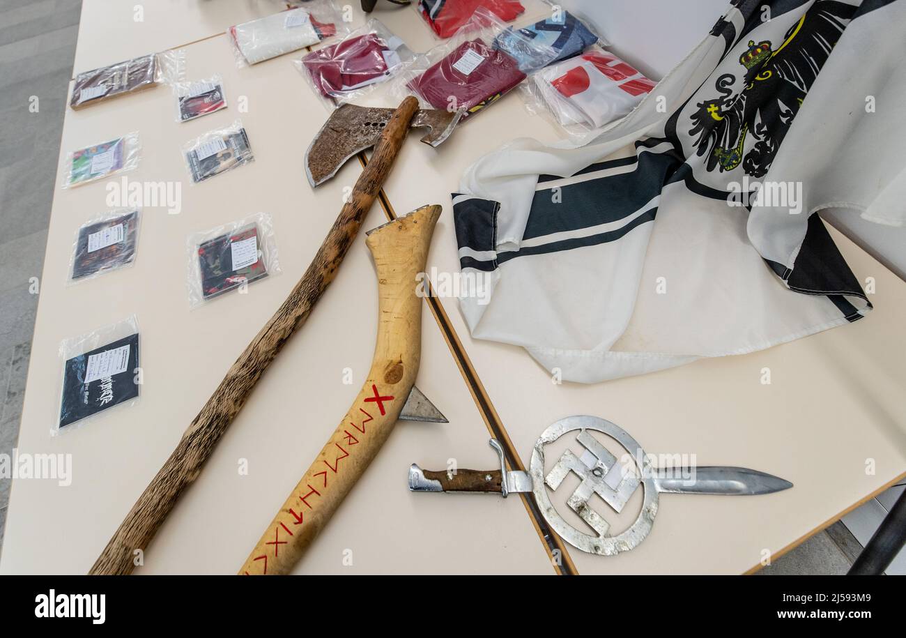 Heilbronn, Deutschland. 21. April 2022. Ein Bajonett mit eingelagertem Hakenkreuz und zwei markeneigenen Achsen, die während eines Polizeieingriffs in Boxberg-Bobstadt beschlagnahmt wurden, liegt mit anderen Beweisen auf einem Tisch im Polizeipräsidium Heilbronn. Bei einer Wohnungsdurchsuchung eines mutmaßlichen Reichsbürgers wegen des Verdachts auf illegalen Waffenbesitz kam es in Boxberg-Bobstadt zu einem Schusswechsel zwischen dem Mann und der Polizei - es gab heute eine Polizeipressekonferenz mit Einzelheiten der Operation. Quelle: Christoph Schmidt/dpa/Alamy Live News Stockfoto