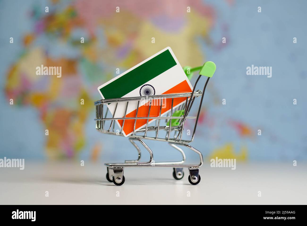 Indische Nationalflagge in Miniatur-Einkaufswagen. Online-Shopping oder Versand, Duty-Konzept. Weltkarte im Hintergrund. Stockfoto