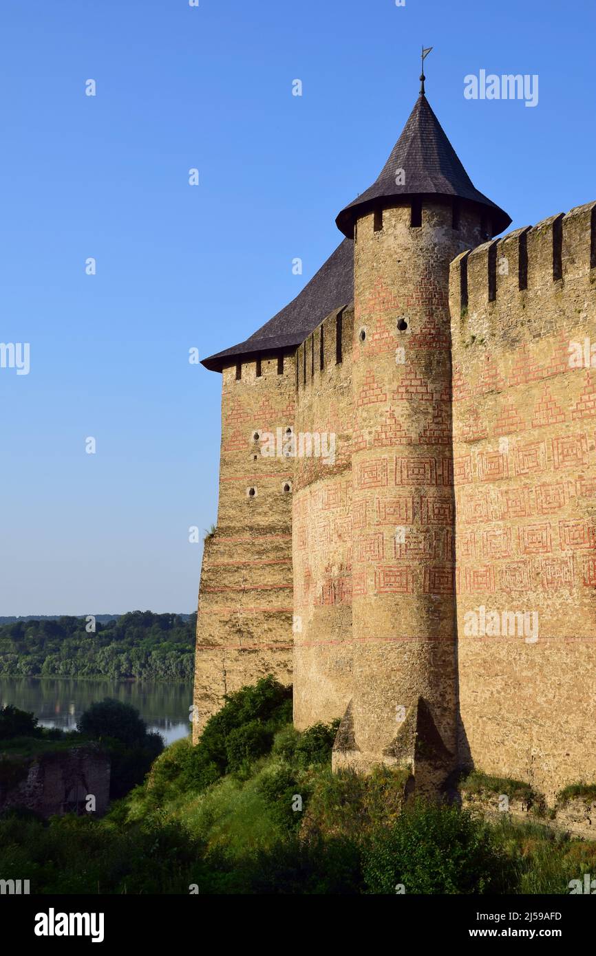 Mittelalterliche Steinfestung mit Türmen mit zinnenverzierten starken Mauern mit Mustern. Linker Fluss und Wald Stockfoto