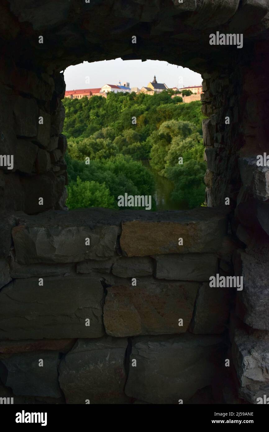 Die Schießschlange der Festung, durch die man den grünen Wald und die Altstadt in einer dicken Mauer mit Mauerwerk sehen kann Stockfoto