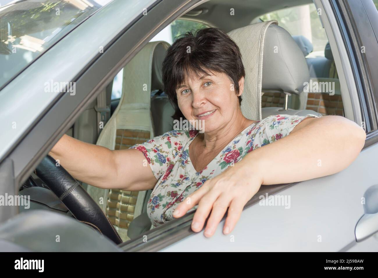 Eine wunderschöne Frau mittleren Alters, die ein Auto fährt Stockfoto