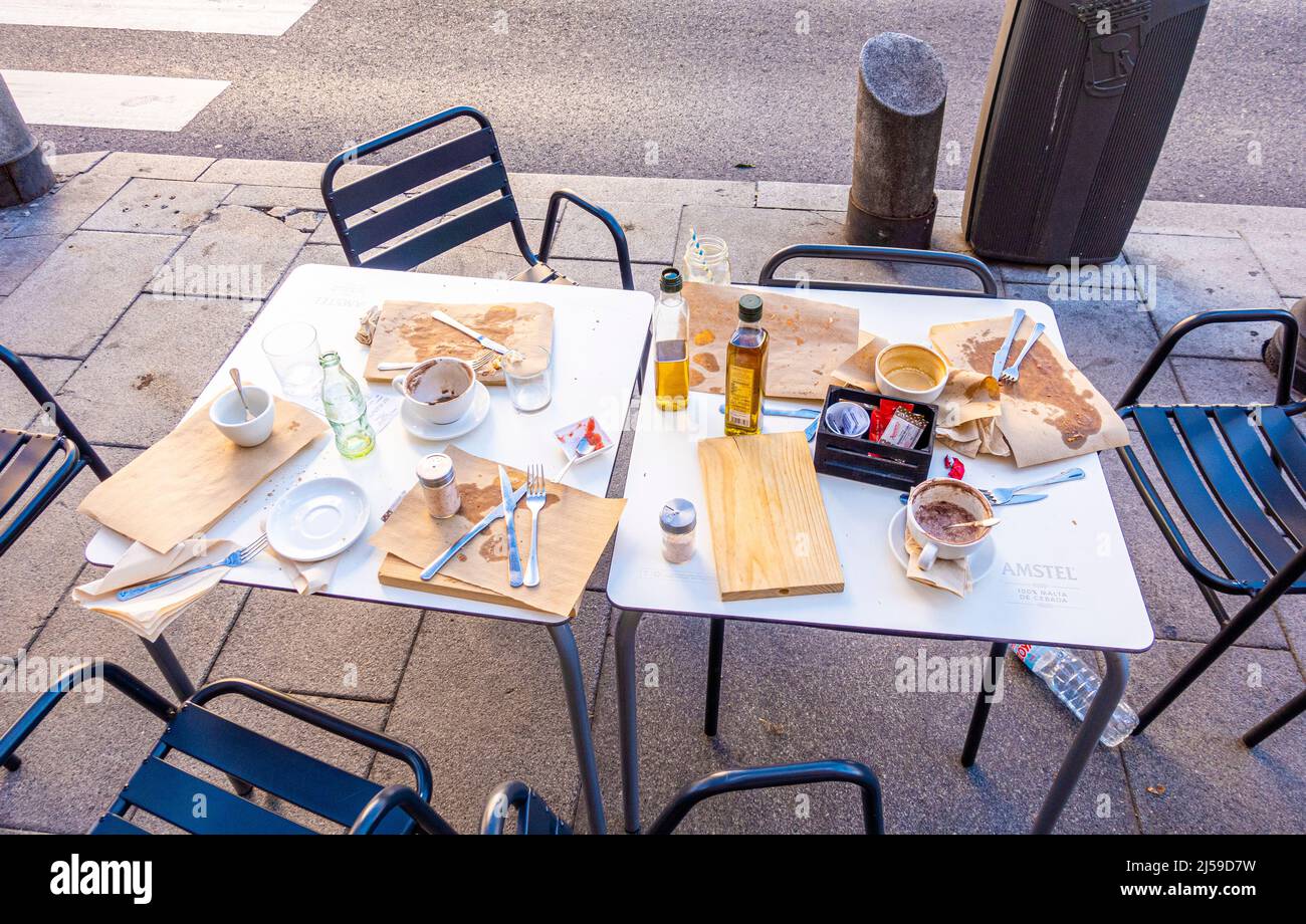 Verlassene Tisch mit Stühlen mit Essensresten, leere Teller, Olivenöl in der Straße im Zentrum von Madrid, Spanien Stockfoto